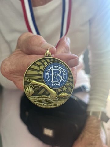 Gold Bondi Icebergs Club medal on a red, white and blue ribbon