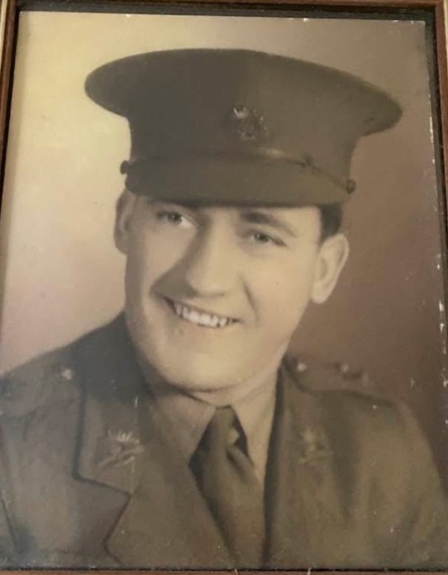Sepia studio portrait of a smiling young Neville Anderson in Australian Army officer's uniform and peaked cap