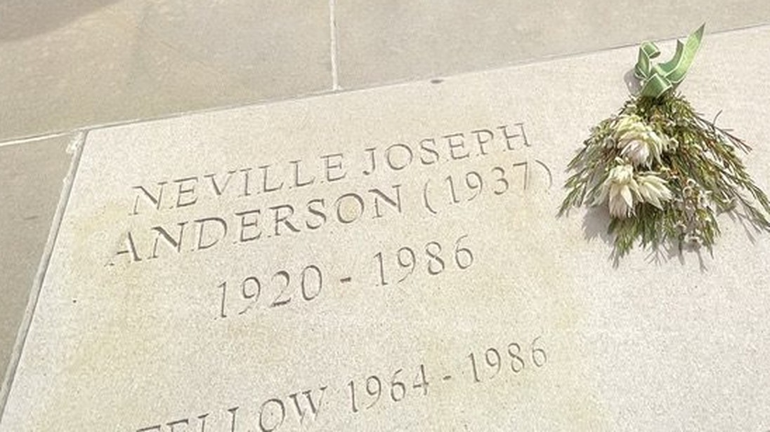 Stone in the paving at St John's College inscribed Neville Joseph Anderson (1937), 1920 – 1986, Fellow 1964 – 1986, with a small bouquet of native flowers